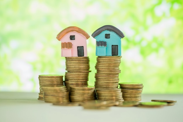 Free Photo mini house on stack of coins with green blur. 