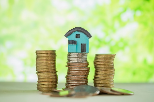 Free photo mini house on stack of coins with green blur.