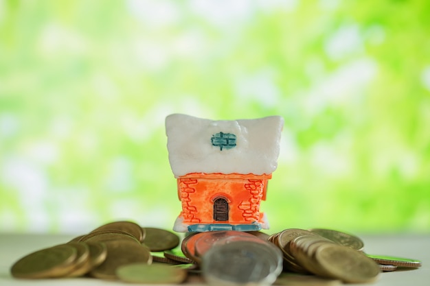 Free photo mini house on stack of coins with green blur.