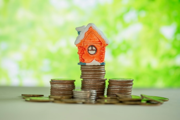 Free photo mini house on stack of coins with green blur.