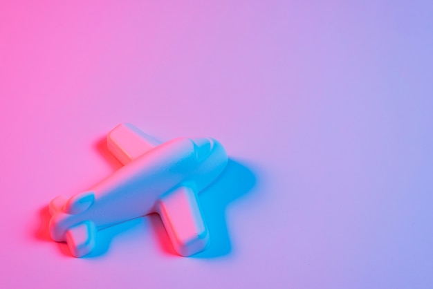 Miniature airplane with blue light on pink backdrop