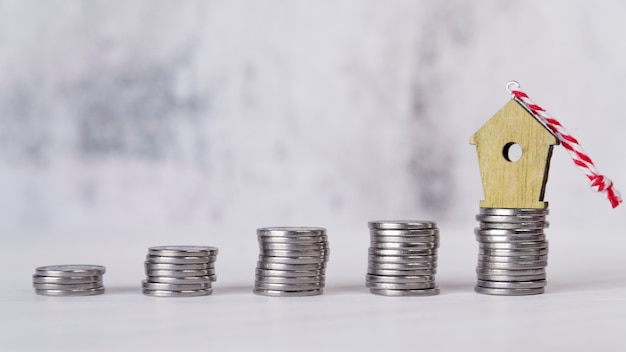 Free photo miniature birdhouse ornament over the increasing stacked of silver coins