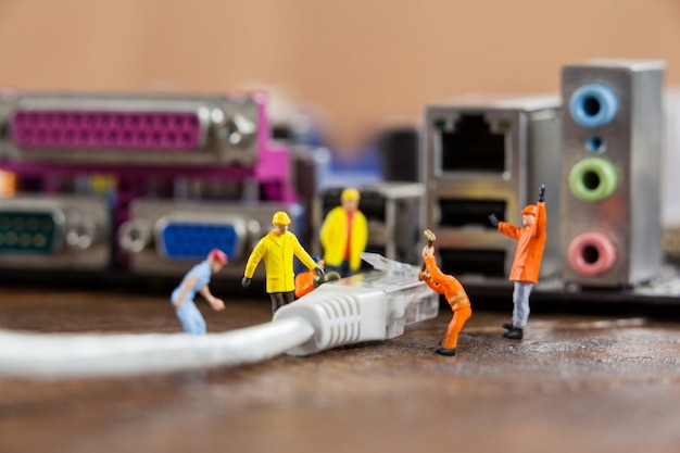 Free photo miniature engineer and worker plug-in lan cable to computer