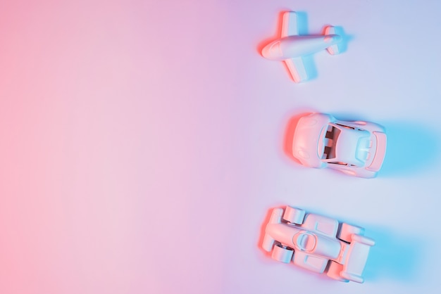 Miniature transport vehicle arranged in a row on pink backdrop