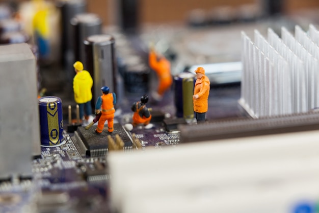 Miniature workers working on chip of motherboard