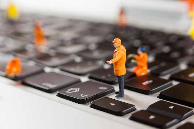 Miniature workmen repairing a laptop keyboard