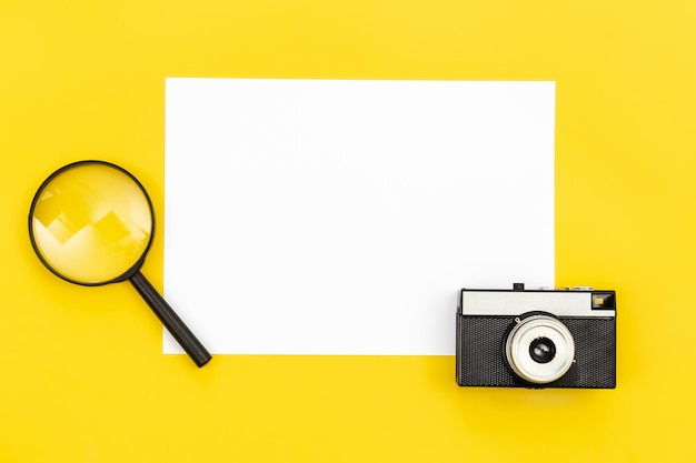 Free photo minimal background with blank paper camera and magnifier flat lay