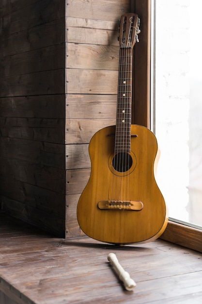 Free photo minimalist concept with wooden walls and classic guitar