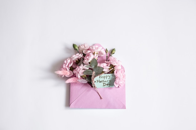 Minimalistic composition for mother's day. Decorative envelope with flowers inside copy space.