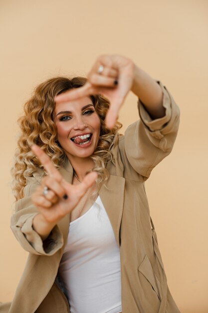 Mirthful young woman smiling and making a frame with her fingers. Fashion concept