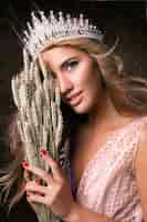 Free photo miss earth woman wearing the crown, ribbon and spikelets of wheat. fashion contest, beautiful model posing