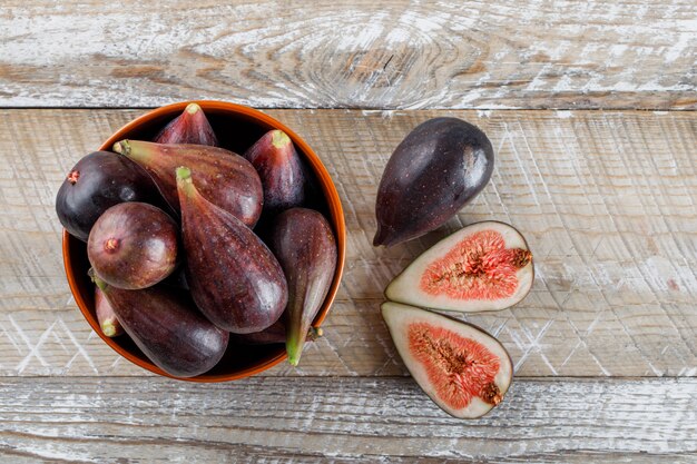 Mission figs and halves in a bowl and around top view on a wooden table