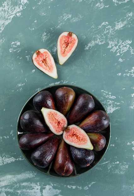 Mission figs and halves in a bowl and nearby flat lay on a teal 