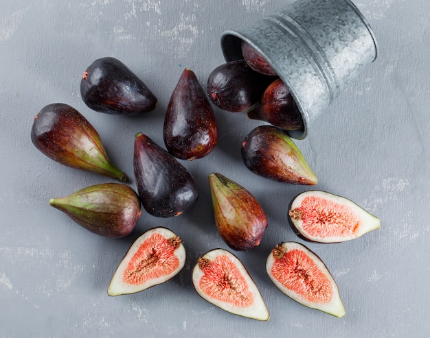 Free photo mission figs and halves coming out of a bucket on a textured background. high angle view.