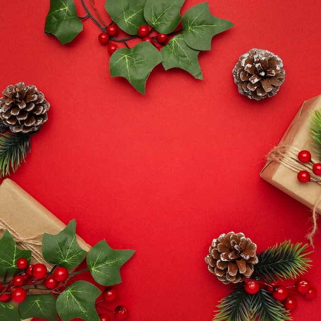 Mistletoe, pine cones and christmas gifts on red table