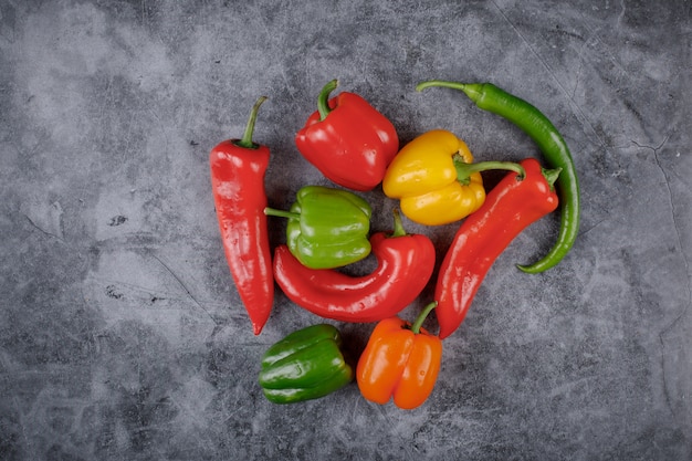 Mixed color bell peppers and chilies in the middle center of the background. Top view.