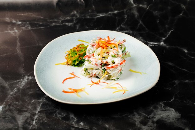 Mixed ingredients salad inside white plate on a black marble.