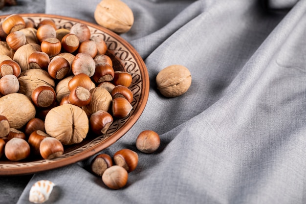 Mixed nuts in a decorative pottery plate isolated on blue tablecloth