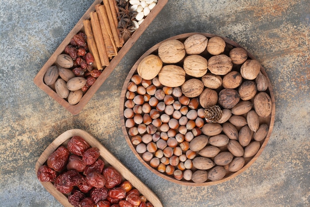 Mixed nuts with cinnamon sticks and dried fruit on wooden plate. High quality photo