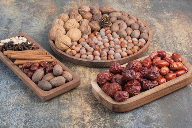 Mixed nuts with cinnamon sticks and dried fruit on wooden plate. High quality photo