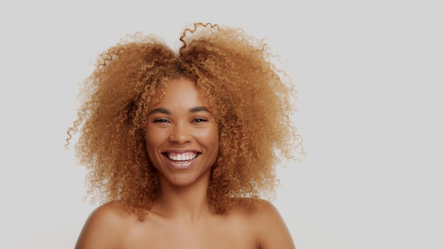 Mixed race black blonde model with curly hair happy smiling touching it