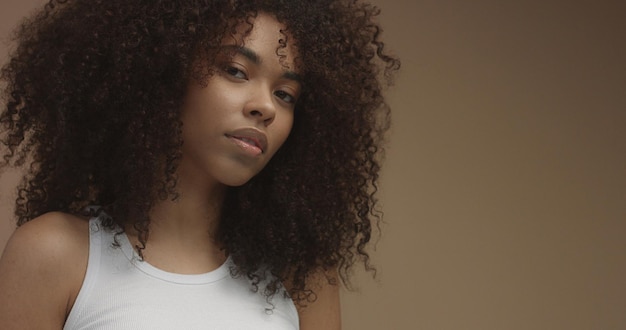 Mixed race black woman portrait with big afro hair curly hair in beige background