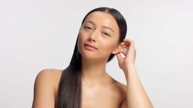 Free photo mixed race model touches her hair and watching to the camera glowy natural ideal skin