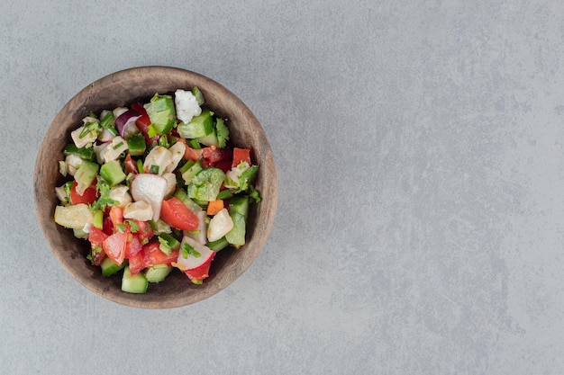 Mixed vegetable salad in a wooden cup on the concrete table.