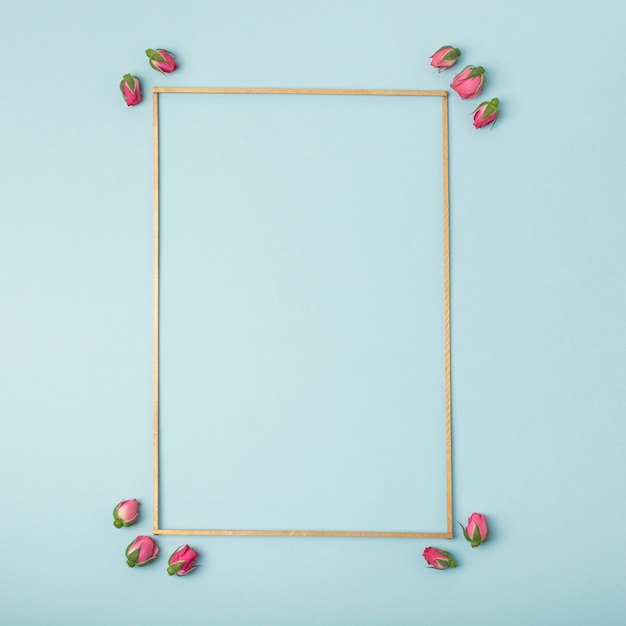 Free photo mock-up empty frame with rosebuds on blue background