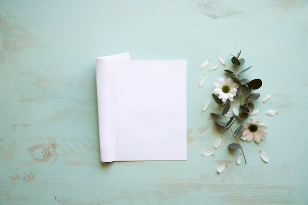 Free Photo mockup of a sheet of paper next to flower