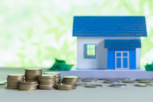 Model of house with coins on wooden table