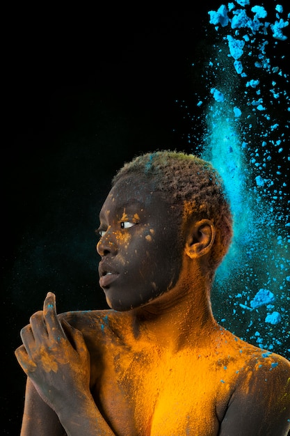 Free photo model posing with yellow and blue powder medium shot