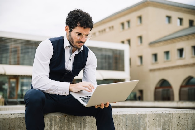 Free photo modern businessman using laptop outdoors