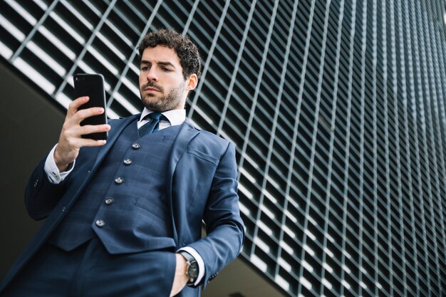 Modern businessman using smartphone outdoors