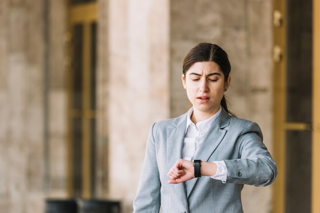 Free photo modern businesswoman looking at watch outdoors