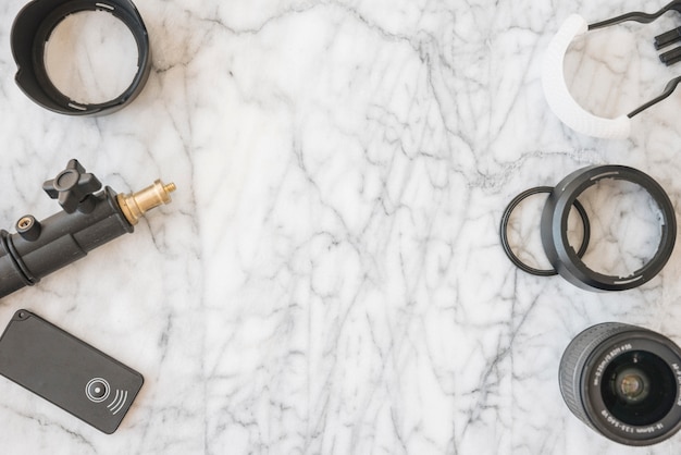 Modern camera lens; extension rings; tripod and accessories on marble background