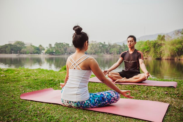 Modern couple meditating next to the lake