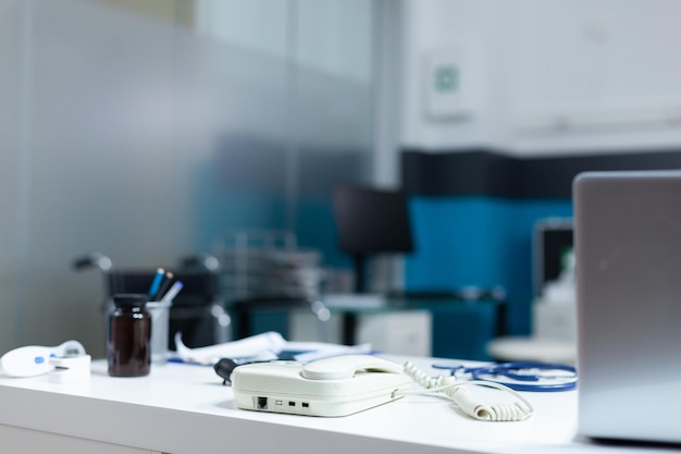 Free photo modern empty doctor office equipped with professional medical instruments ready for clinical consultation. hospital room with nobody in it having otoscope and landline on desk table. medicine concept