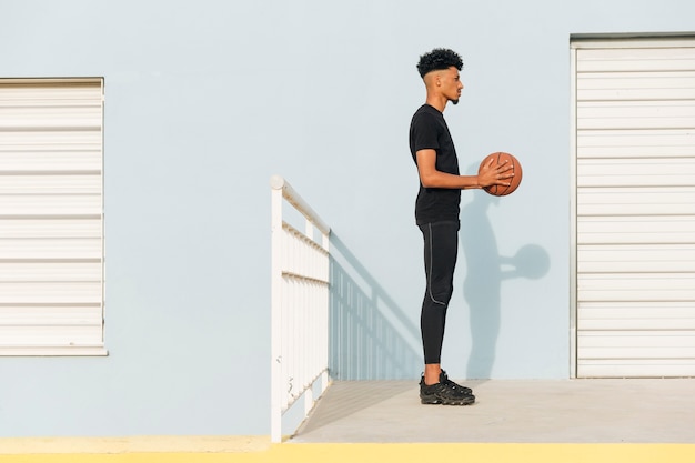 Free Photo modern ethnic man with basketball on street 