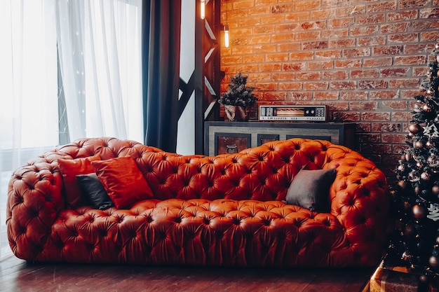 Free Photo modern fashionable red leather couch with cushions. cropped christmas tree. brick wall. loft design.