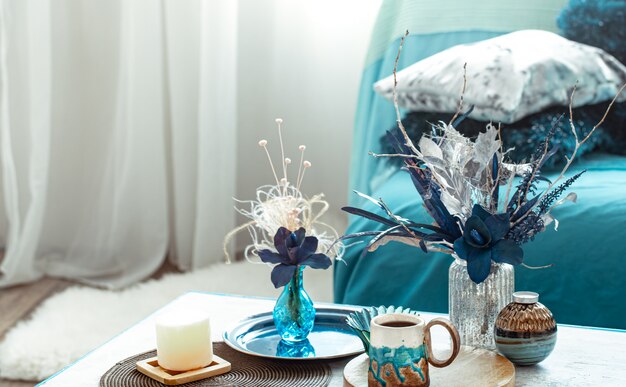 Modern living room, with artificial flowers in a vase and home decor items on wooden light table.