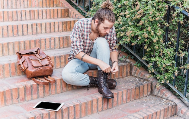 Free Photo modern man tying shoes on stairs