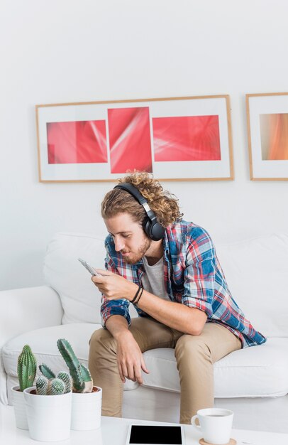 Modern man with smartphone on couch