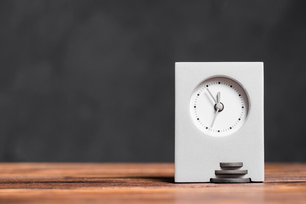 Modern rectangular clock on textured wooden desk against black background