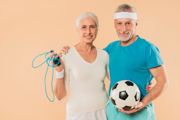 Free Photo modern senior couple with skipping rope and football