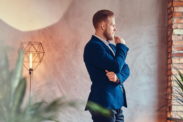 A modern, stylish male dressed in an elegant suit posing in a room with loft interior.