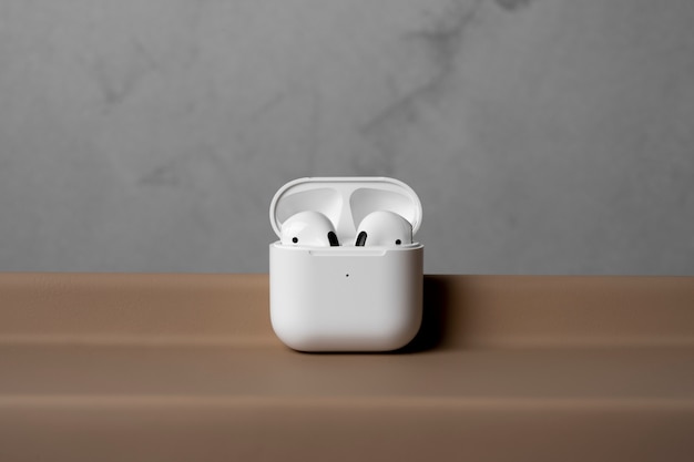 Free photo modern wireless earphones with case and simple concrete background