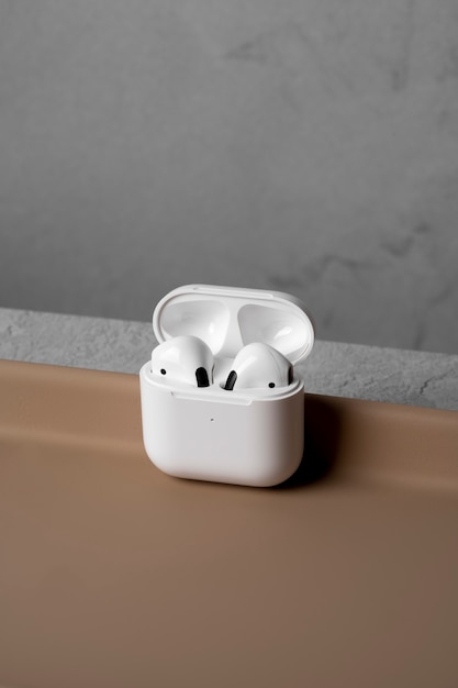 Free photo modern wireless earphones with case and simple concrete background