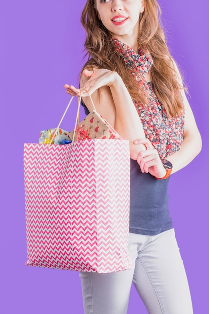 Free photo modern woman holding shopping bag full of wrapped gift