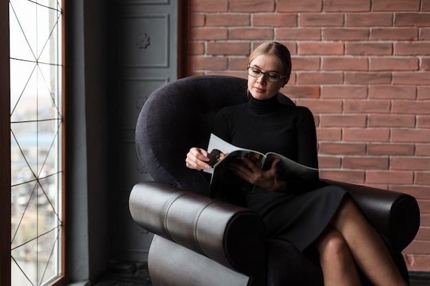 Free Photo modern woman relaxing on couch with magazine